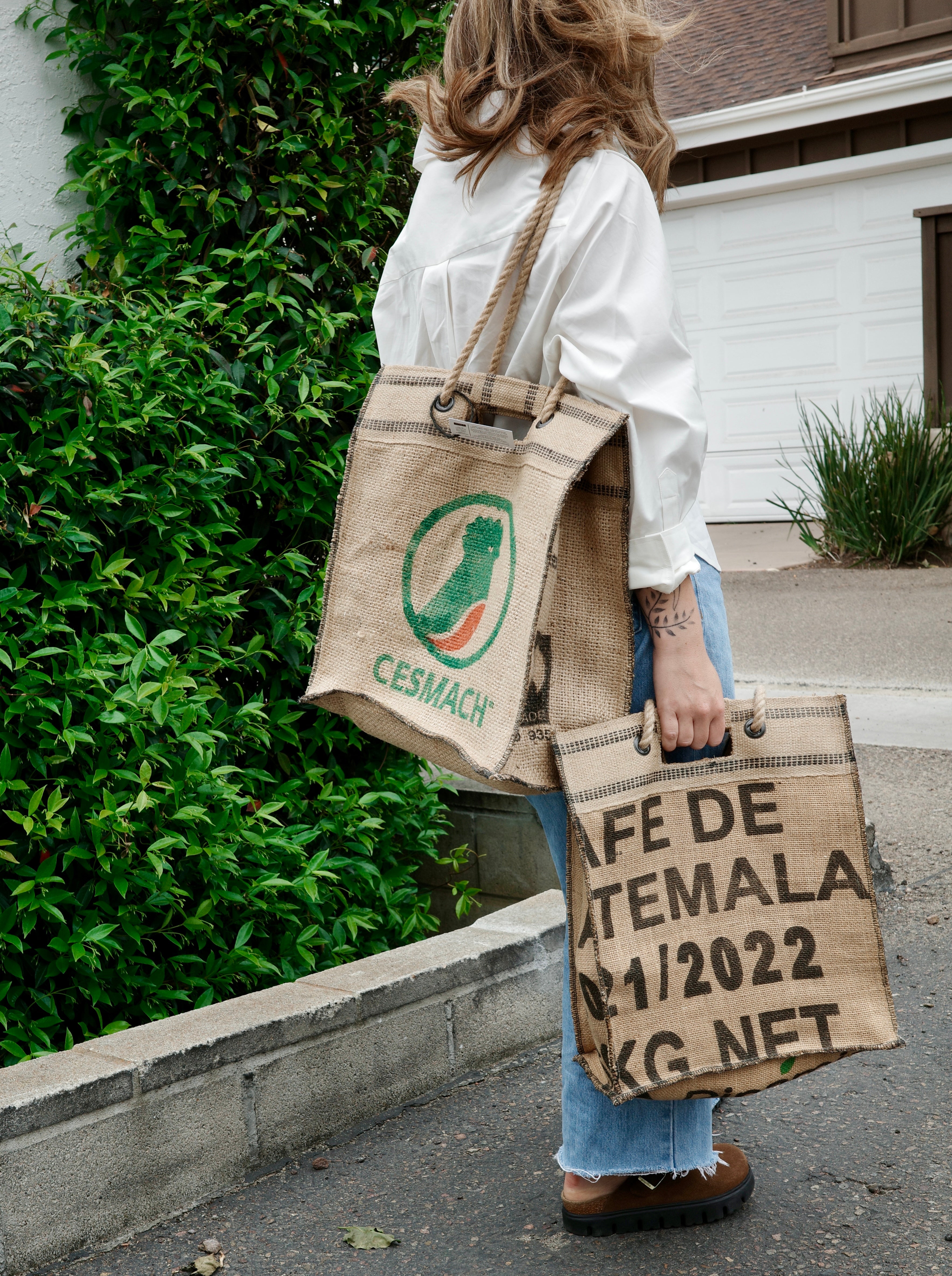 Two custom coffee sack bags carried outdoors